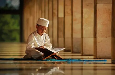 A young boy with a Mushaf in hand